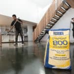 Contractor installing polished concrete floor in an open-plan room. Bag of Stopgap 800 in foreground.